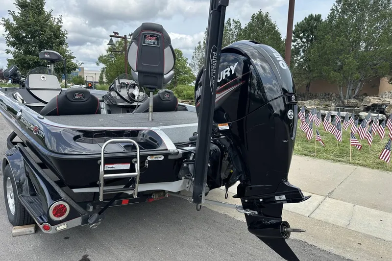 Slide: The Image of 2018 Ranger Z518 boat with Mercury engine, parked near American flags on a trailer. - 6
