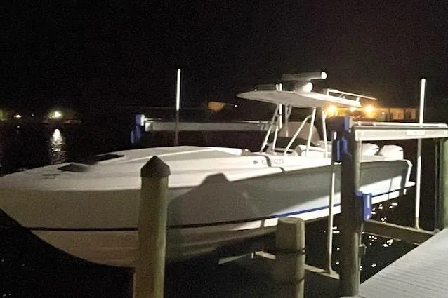 Slide: The Image of 2002 Intrepid 323 Cuddy boat docked at night, illuminated by nearby lights. - 2