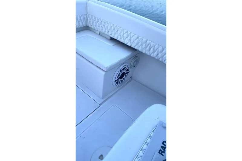 Slide: The Image of 2002 Intrepid 323 Cuddy boat interior with cushioned seating and speaker detail. - 7