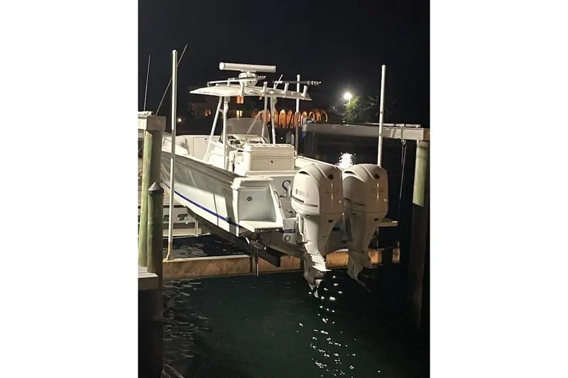 Slide: The Image of 2002 Intrepid 323 Cuddy boat docked at night with dual outboard engines. - 12