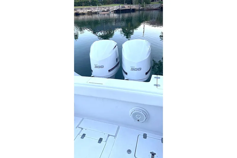 Slide: The Image of Twin Yamaha 300 engines on a 2002 Intrepid 323 Cuddy boat, docked by calm waters. - 4