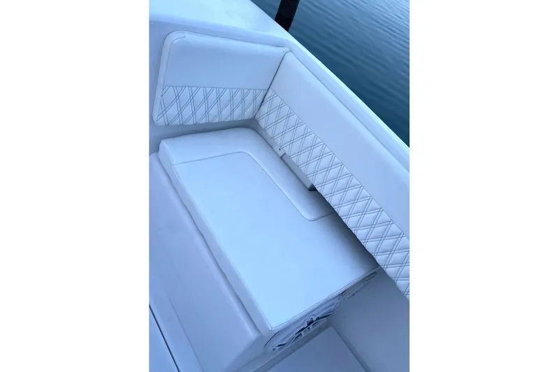 Slide: The Image of White cushioned seating on a 2002 Intrepid 323 Cuddy boat, featuring diamond-pattern stitching. - 15