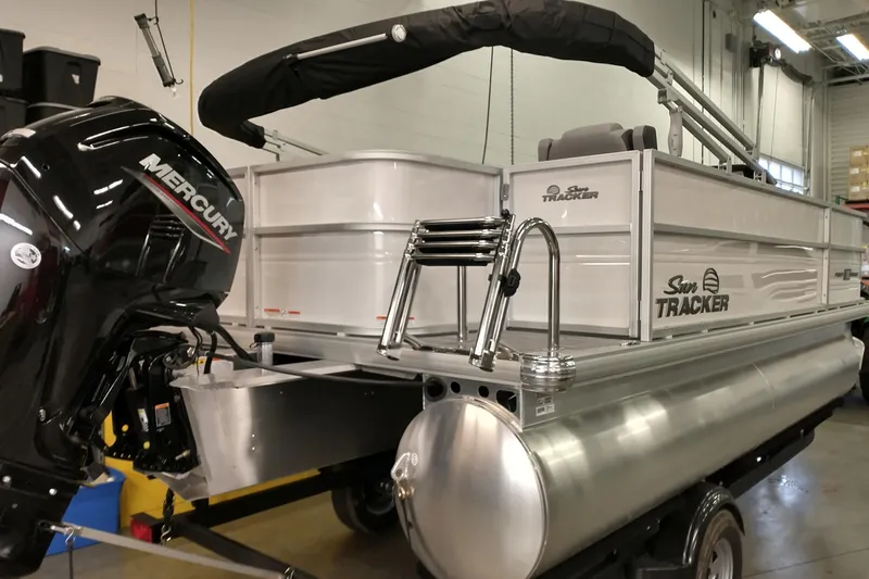 Slide: The Image of 2026 Sun Tracker Party Barge 18 DLX pontoon boat with Mercury engine in a showroom. - 2