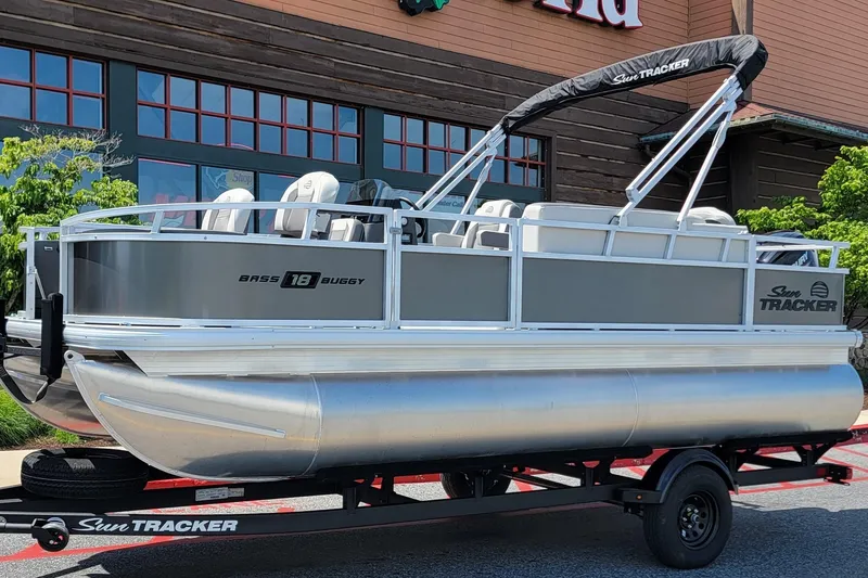 The Image of 2026 Sun Tracker Bass Buggy 18 DLX pontoon boat on trailer, parked outdoors. - 0