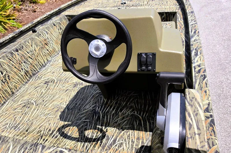 Slide: The Image of 2026 Tracker Grizzly 1648 SC boat interior with camouflage design and steering wheel. - 9