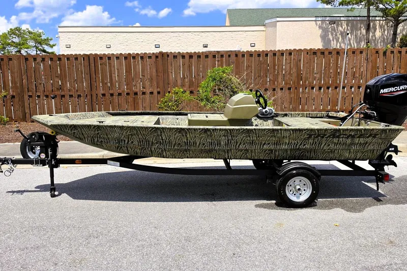 Slide: The Image of 2026 Tracker Grizzly 1648 SC boat on trailer, camo design, parked outdoors. - 5