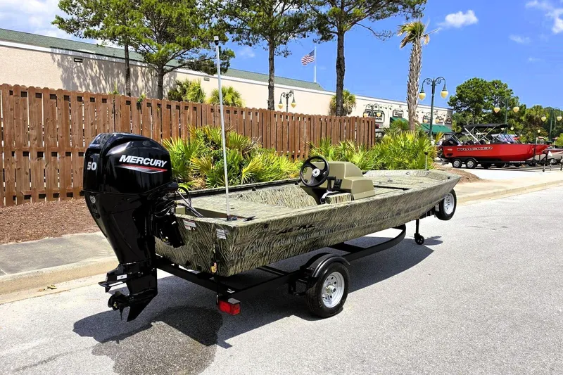 Slide: The Image of 2026 Tracker Grizzly 1648 SC boat with Mercury engine on trailer, parked outdoors. - 2