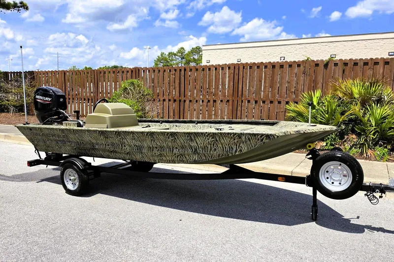 Slide: The Image of 2026 Tracker Grizzly 1648 SC boat on trailer, camo design, parked outdoors. - 3