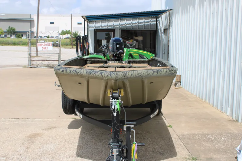 Slide: The Image of 2026 Tracker Grizzly 1650 T Prairie Wings Edition boat on trailer outside warehouse. - 2