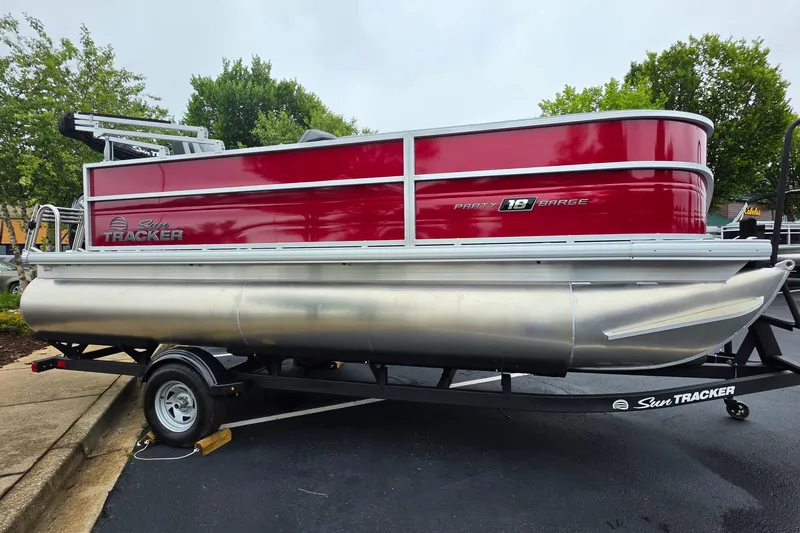 The Image of 2026 Sun Tracker Party Barge 18 DLX pontoon boat on trailer, vibrant red exterior. - 0
