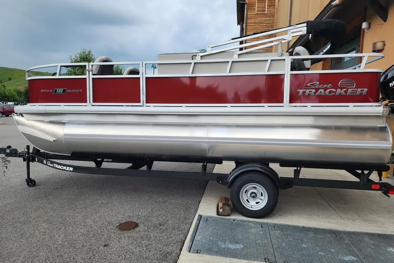 The Image of 2026 Sun Tracker Bass Buggy 18 DLX pontoon boat on trailer, parked outdoors. - 0