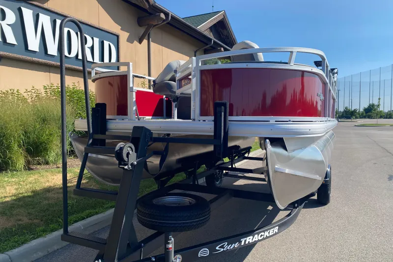 Slide: The Image of 2026 Sun Tracker Bass Buggy 18 DLX pontoon boat on trailer, parked outdoors. - 1