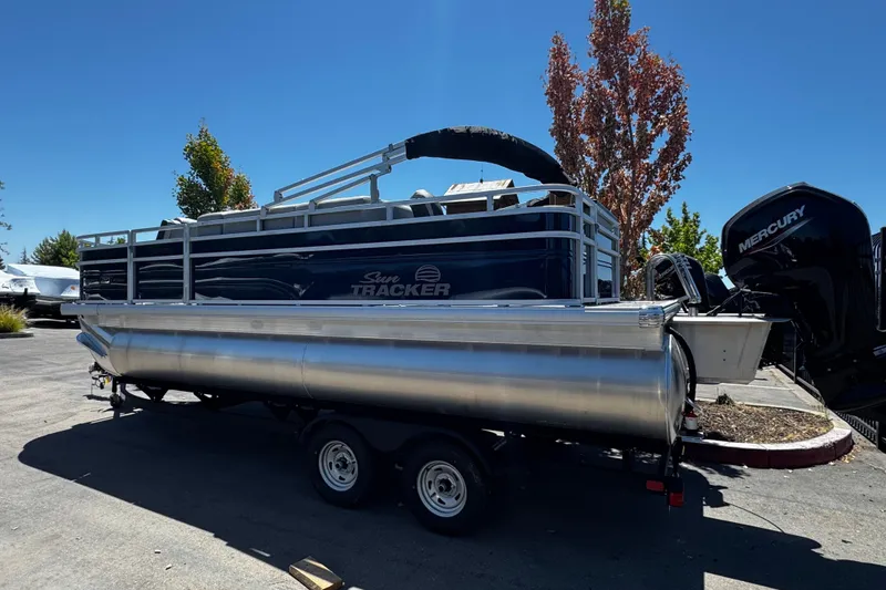 Slide: The Image of 2026 Sun Tracker SportFish 20 DLX pontoon boat on trailer, parked outdoors. - 2