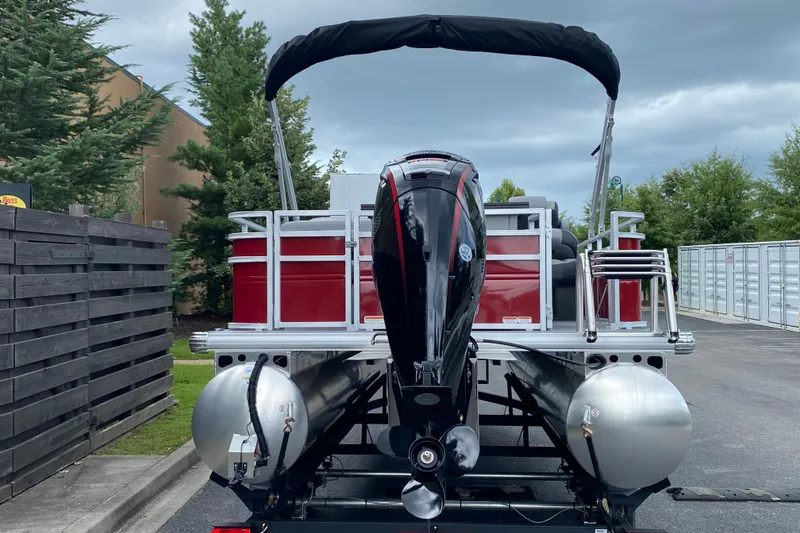 Slide: The Image of 2026 Sun Tracker SportFish 20 DLX pontoon boat with outboard motor, parked outdoors. - 2