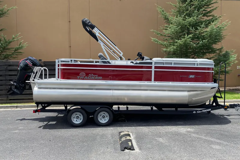 The Image of 2026 Sun Tracker SportFish 20 DLX pontoon boat on trailer, red and silver design. - 0