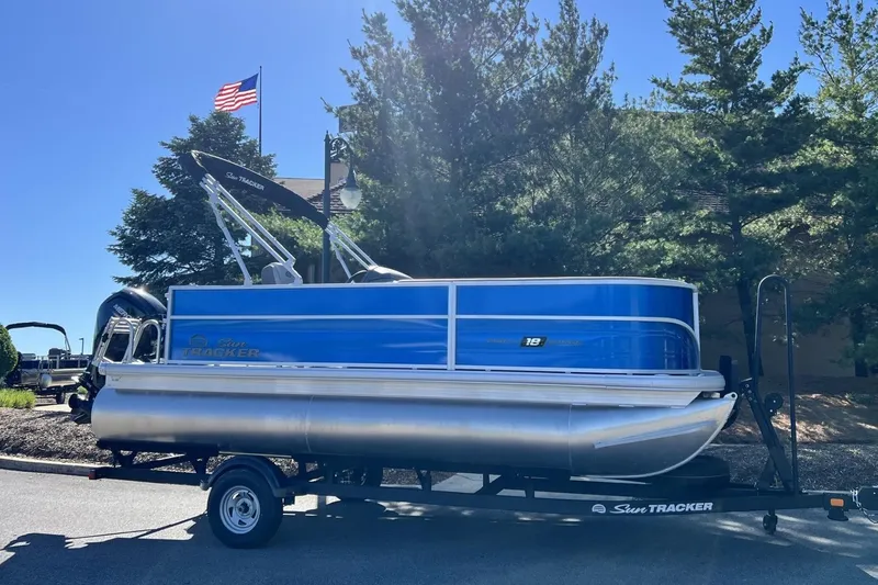 The Image of 2026 Sun Tracker Party Barge 18 DLX pontoon boat on trailer, outdoors. - 0