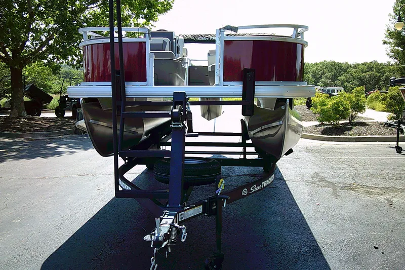 Slide: The Image of 2026 Sun Tracker Bass Buggy 18 DLX pontoon boat on trailer, parked outdoors. - 4