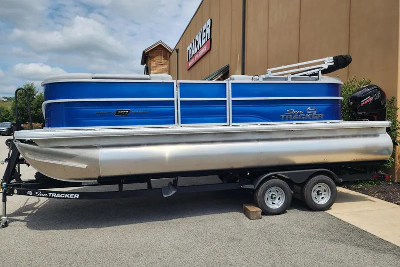 The Image of 2026 Sun Tracker Party Barge 20 DLX pontoon boat on trailer, parked outdoors. - 0