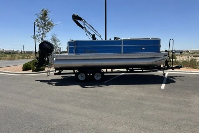 The Image of 2026 Sun Tracker Party Barge 20 DLX pontoon boat parked on a trailer in a lot. - 0