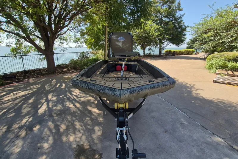 Slide: The Image of The image shows a Tracker Grizzly 1650 T Prairie Wings Edition boat on a trailer, surrounded by trees. - 2