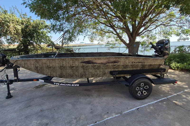 The Image of 2026 Tracker Grizzly 1650 T Prairie Wings Edition boat on trailer, parked near trees. - 0