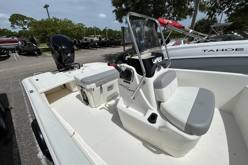 Slide: The Image of 2026 Mako Pro Skiff 17 CC boat with center console and outboard motor in a parking lot. - 4