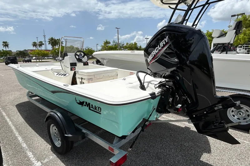 Slide: The Image of 2026 Mako Pro Skiff 17 CC boat with Mercury engine on trailer, parked outdoors. - 2