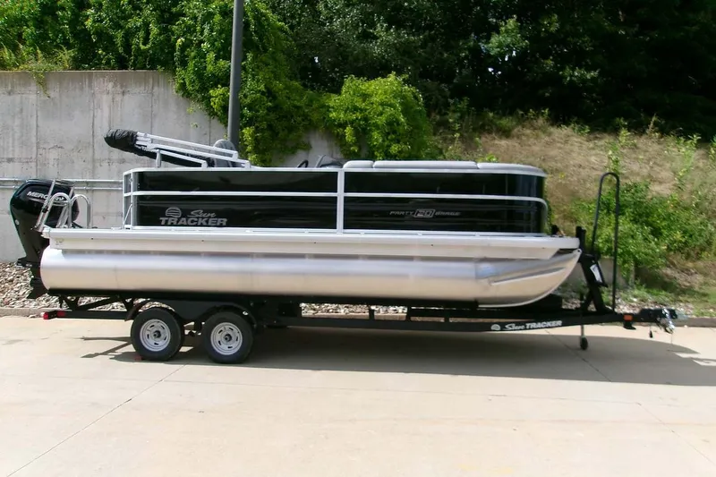 The Image of 2026 Sun Tracker Party Barge 20 DLX pontoon boat on trailer, parked outdoors. - 0