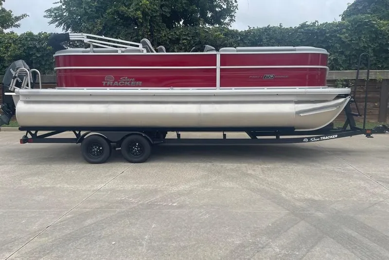 Slide: The Image of 2026 Sun Tracker Party Barge 22 XP3 pontoon boat on trailer, parked outdoors. - 1