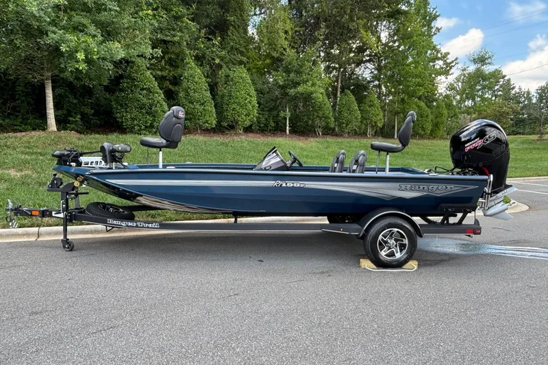 The Image of 2026 Ranger RT198P fishing boat on trailer, parked on road with lush greenery background. - 0