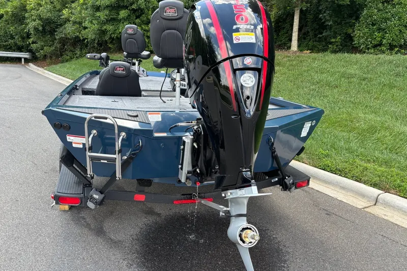 Slide: The Image of 2026 Ranger RT198P boat with powerful outboard motor, parked on a road near greenery. - 6