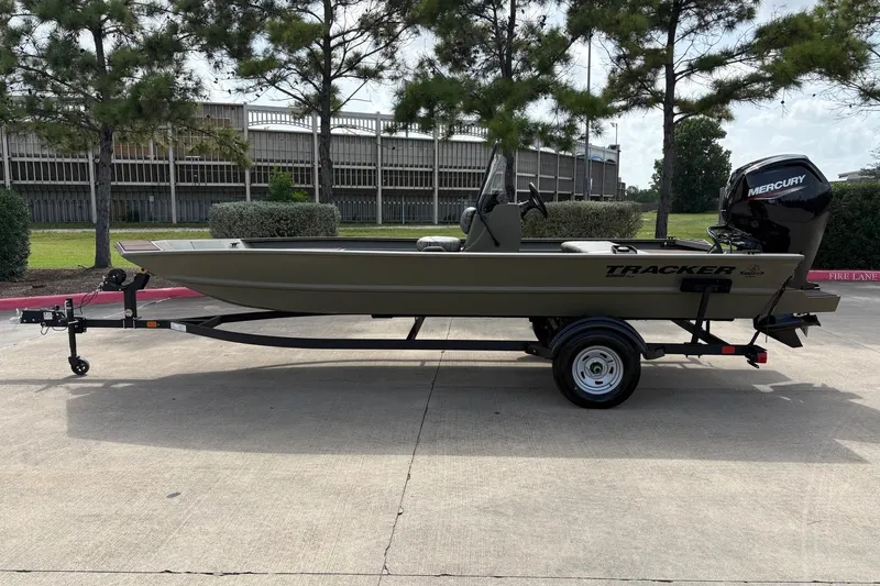 The Image of 2026 Tracker Grizzly 1860 CC boat on trailer, parked outdoors with trees in background. - 0
