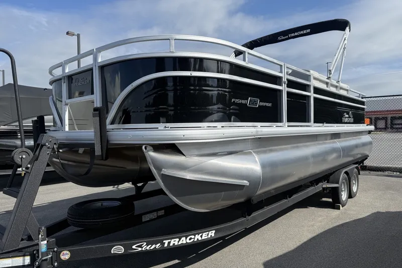 The Image of 2026 Sun Tracker Fishin' Barge 22 DLX pontoon boat on trailer, parked outdoors. - 0
