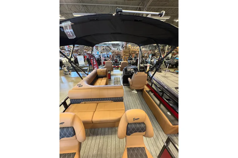 Slide: The Image of 2026 Ranger 223FC boat interior with tan seating and black canopy in showroom. - 9