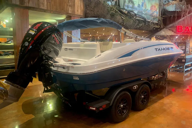 Slide: The Image of 2026 Tahoe 1950 boat with outboard motor displayed indoors on a trailer. - 1