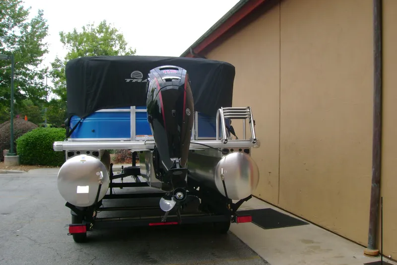 Slide: The Image of 2026 Sun Tracker Party Barge 20 DLX pontoon boat with covered motor, parked outdoors. - 9