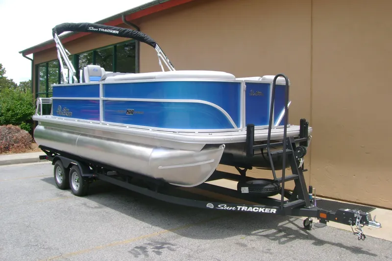 Slide: The Image of 2026 Sun Tracker Party Barge 20 DLX pontoon boat on trailer, parked outdoors. - 2