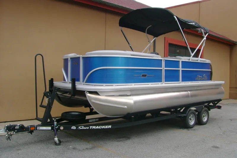 Slide: The Image of 2026 Sun Tracker Party Barge 20 DLX pontoon boat on trailer, blue exterior, parked outdoors. - 3