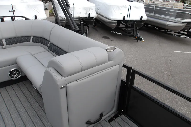Slide: The Image of 2026 Ranger 223FC boat interior with gray seating and cup holder, parked near other boats. - 17