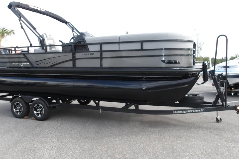 The Image of 2026 Ranger 223FC pontoon boat on trailer, sleek design, dual-axle wheels, outdoor setting. - 1