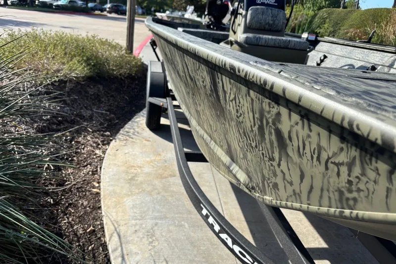 Slide: The Image of 2026 Tracker Grizzly 2072 CC boat on trailer, camo design, parked outdoors. - 2