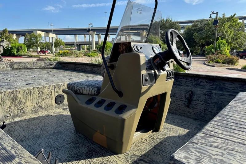 Slide: The Image of 2026 Tracker Grizzly 2072 CC boat interior with steering console, camo design, and outdoor setting. - 8