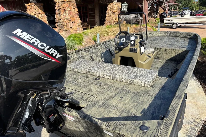 Slide: The Image of 2026 Tracker Grizzly 2072 CC boat with Mercury engine, camo design, parked outdoors. - 6