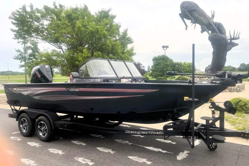 Slide: The Image of 2026 Ranger VX1988 WT boat on trailer, parked near a tree and sculpture. - 9