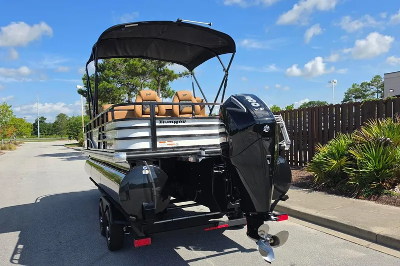 Slide: The Image of 2026 Ranger 223FC pontoon boat with powerful outboard motor, parked on sunny street. - 13