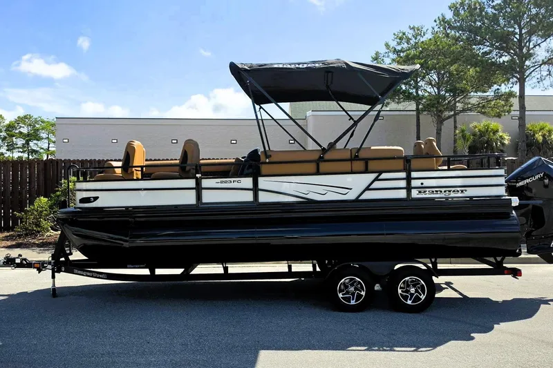 Slide: The Image of 2026 Ranger 223FC pontoon boat with canopy on trailer, parked outdoors. - 10