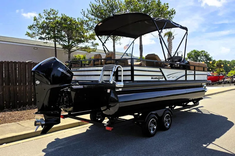 Slide: The Image of 2026 Ranger 223FC pontoon boat with Mercury engine on a trailer, parked outdoors. - 3