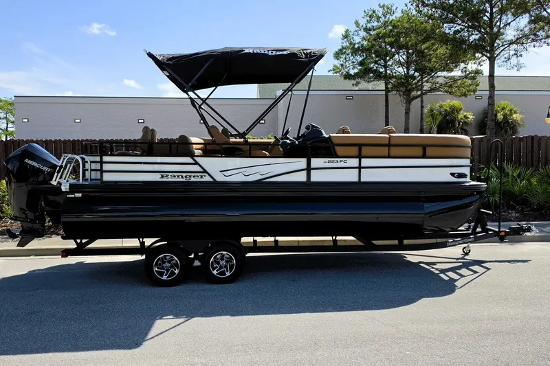 Slide: The Image of 2026 Ranger 223FC pontoon boat on trailer, featuring a sleek design and canopy. - 1