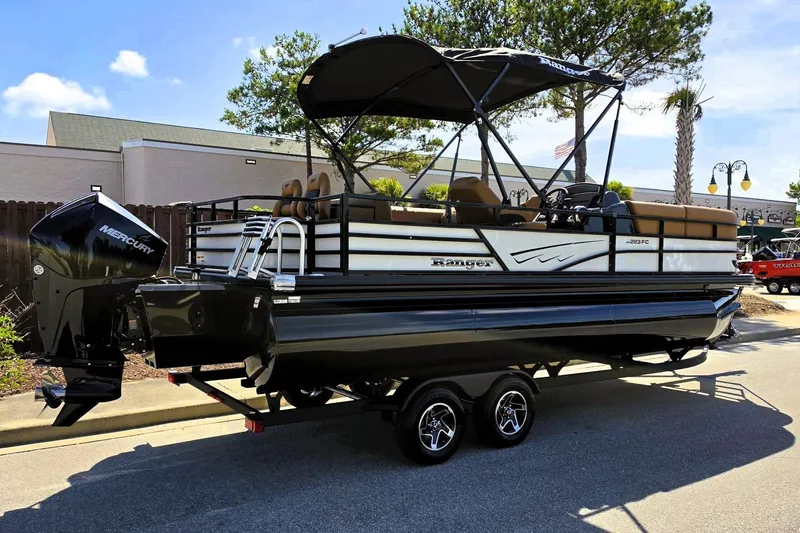 Slide: The Image of 2026 Ranger 223FC pontoon boat with Mercury engine on a trailer, parked outdoors. - 2