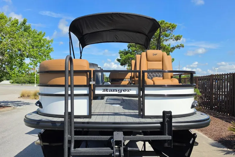 Slide: The Image of 2026 Ranger 223FC pontoon boat with tan seats and black canopy, parked outdoors. - 8